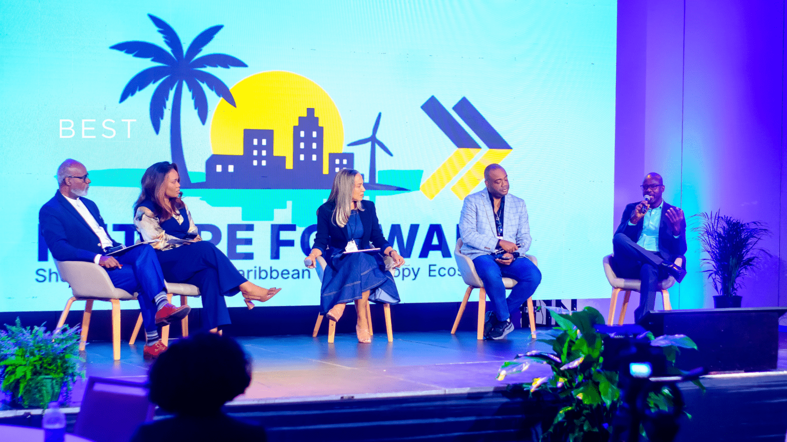 A group of people participating in a conference or event about sustainable Caribbean communities and eco-friendly economy, as shown on the stage backdrop.